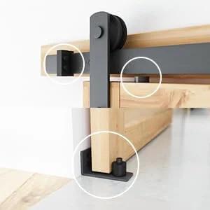 Close-up of 8.2 FT Heavy Duty Sturdy Sliding Barn Door Hardware Kit, Black, showing door rollers and floor guide on wooden panel