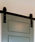 Barn Door Hardware Track Connector Splicing Plate Kit for Sliding Barn Doors installed on a grey door with black hardware