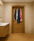 Bathroom with wooden door and towels hung on hooks, modern sink and mirror on the left.