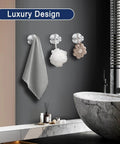 Bathroom with luxury design featuring three wall hooks holding a gray towel, white bath sponge, and beige flower-shaped decor item.