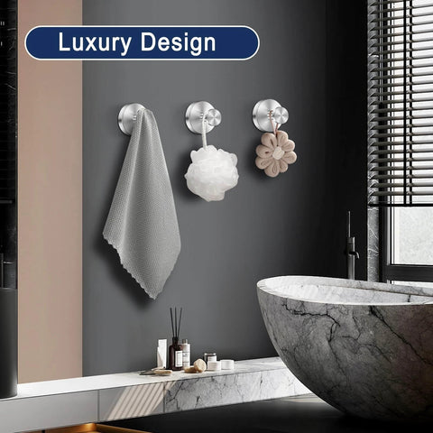 Bathroom with luxury design featuring three wall hooks holding a gray towel, white bath sponge, and beige flower-shaped decor item.