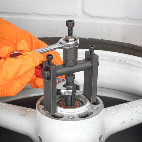 Using 10pc Bridge Bearing Puller Set to remove bearing from wheel hub with wrench, showing extractor and collets in action.