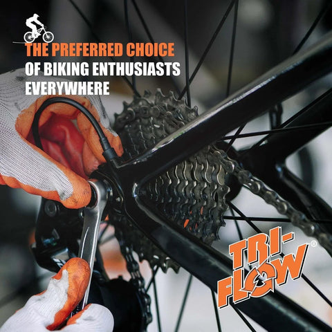 Hands applying lubricant to bicycle gear with Tri-Flow logo and text 'The Preferred Choice of Biking Enthusiasts Everywhere'
