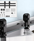 Close-up of 60" Bi-Folding Sliding Barn Door Hardware Kit for Two 28" Bifold Doors showing black metal parts and roller system.