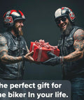 Two motorcyclists in leather vests exchanging a wrapped gift, wearing helmets, smiling, with the text 'The perfect gift for the biker in your life.'