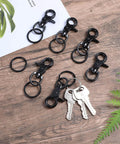 Six Pcs Black 60mm Zinc Alloy Trigger Carabiner Heavy Duty Swivel Snap Hooks With 360 Degree Rotatable Eye Clips on wooden surface