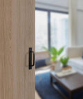 12 Pack Black Barn Door Handles 5.8 Inch Aluminum Alloy Cabinet Pulls With 24 Screws installed on a wooden sliding door in living room.