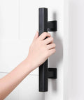 Hand holding Heavy Duty 12" Pull and Flush Barn Door Handle Set, Large Rustic Two-Side Design, Solid Steel Square Black on white door
