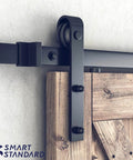 Close-up of 10FT Sliding Barn Door Hardware Kit, black J shape hanger on a wooden door panel, heavy duty track-mounted.