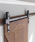 6ft Heavy Duty Sliding Barn Door Hardware Kit, Black shown installed on wood door with big industrial wheel hangers for 36" panels