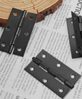 12 Pack 2.5 Inch Black Butt Door Hinges With Ball Bearing For Cabinets And Windows placed on a wooden and paper background