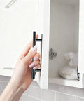 Hand installing black ABS plastic push-pull cabinet handle on a white door with no drill adhesive from 30 Pack Self Stick Push Pull Cabinet Handles.