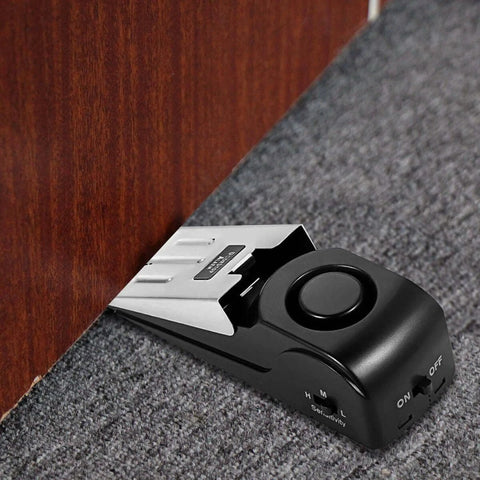 Black Door Stop Alarm with 120DB Siren for Home & Travel installed under wooden door on carpet