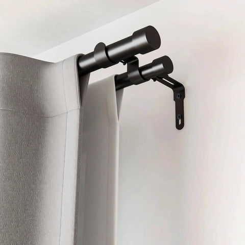 Black double curtain rod with wall brackets, holding gray curtains in a living room setting.
