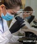 Person wearing Black Dragon 6mil Disposable Latex Gloves for Food Processing and Automotive using a microscope in a lab