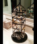 Black jewelry holder with multiple earrings displayed, made from metal, situated on a countertop