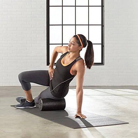 Woman using High Density 12 Inch Foam Roller for Exercise and Recovery in Black in gym setting.