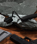 Two Pack Foldable Carry Handles With Non Slip Grip And Aluminum Base, installed on Picatinny rail, 50 lb load capacity, shown on rock surface.
