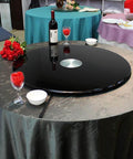 Heavy Duty Black Glass Lazy Susan Turntable set on a table with wine and glasses, ideal for family dinners and elegant presentation.