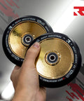 Person holding 110mm AIR Scooter Wheels Black Gold Lightweight Durable Pro Scooter Wheels Designed for Smooth Control Easy Installation