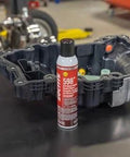 598 Black High Temp RTV Silicone Sealant For Auto Use OEM Approved Performance Engine Building And Repair Grade Heat Resistant Adhesive Sealant Durable Gasket Maker For Intake Exhaust And Engine Surfaces next to engine part on workbench.