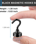Black magnetic hook held between fingers, showing dimensions 1.38 inch height and 0.63 inch diameter, used for hanging items.