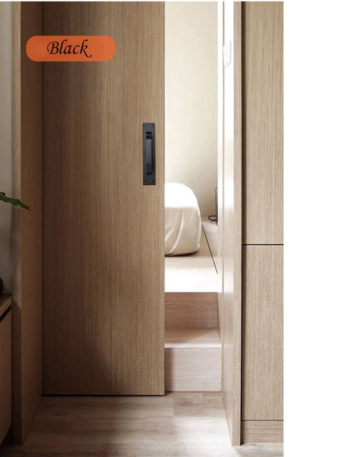 Room view of the 2 Pack Black Matte Finish Barn Door And Cabinet Pull Handles installed on a wooden sliding door, highlighting the sleek design.