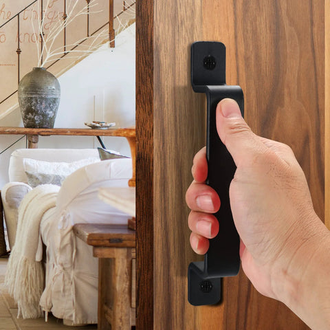 Hand gripping 7.4 inch black sliding barn door handle installed on wood surface, highlighting durable metal pull design for indoor use.