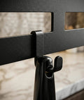 Close-up of wall mount utensil rack showing metal hook detail and installation on marble countertop.