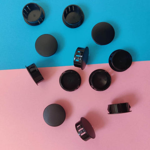 12 Pack Black Plastic Hole Plugs For Cabinet And Screw Holes, 25mm Size Fits 24.5 To 25mm Openings scattered on colored surface