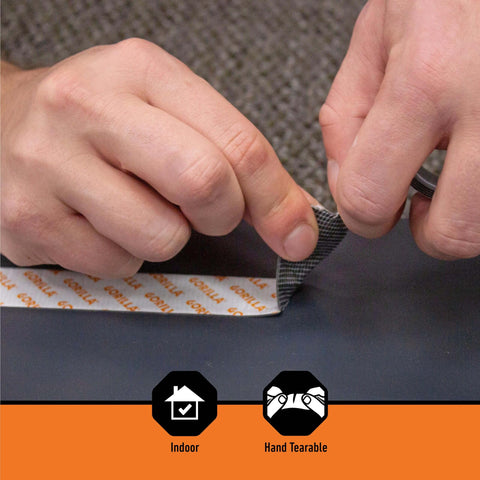 Hands tearing heavy duty mounting tape that sticks like a champ with double sided adhesive and instant hold, one inch by sixty inches