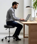 Man sitting on a Rolling Exam Stool with Wheels, 18.5 Inch to 25 Inch Adjustable Height for Dentists, Spas, & Healthcare Environments, 5 Casters, Easy Assembly, Black.