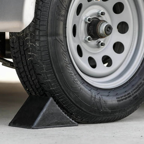 Beefy Rubber Wheel Chock For Cars Trailers RVs And Utility Vehicles With Reinforced Grip Weather And Chemical Resistant 5x6x5 Inch Tire Stopper For Secure Parking And Service Bays Buyers Products WC1467A installed on vehicle tire.
