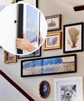 Person hanging a picture frame on a wall using 140pcs Black Self Drilling Drywall Anchors Kit with #8 Flat Head Screws