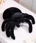Ultra Soft Black Spider Plush Toy For Kids And Adults on a table, huggable jumping spider stuffed animal pillow, adorable decor for Halloween