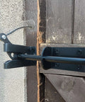 Self Locking Gate Latch For Outdoor Fences In Black Steel With Automatic Gravity Lever Lock Installed on Wooden Gate