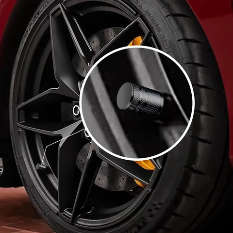 Close-up of 4 Piece Black Anodized Aluminum Plastic Composite Tire Valve Stem Caps With Integrated Plastic Sleeve on car wheel