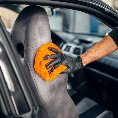 Person wearing Black Vinyl Disposable Exam Gloves 4 Mil Latex Free Powder Free Medical 1000 cleaning car seat with orange cloth