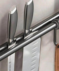 Close-up of Modern Kitchen Utensil Rack, Black Wall-Mounted Hanging Rod with 6 Movable Hooks holding knives and a wooden utensil.