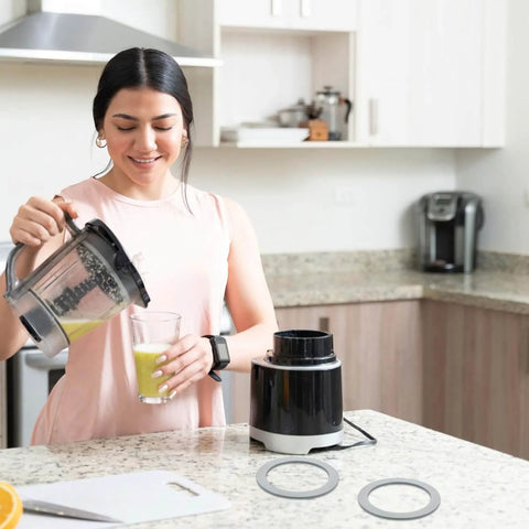 Woman in kitchen with blender, two gray rubber seals for 2 Pack Blender Gasket O-Ring Replacement For Oster Osterizer Blenders.