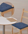 Wooden chair with blue cushion next to round white table with laptop, focus on cushion detail.
