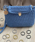 24 Pack Spring O Rings With Trigger Snap Buckles Keychain Rings For Bags And Purses 1 Inch Alloy Rings in various colors around a blue crochet bag.