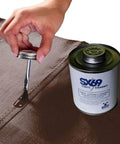 Hand applying 4oz SX-69 adhesive from a can onto a surface, part of the Vinyl Repair Kit For Inflatables With 12x60 Inch Blue Marble Patch Roll