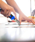 Person using a utility knife from 160-Piece Home Repair Tool Kit With Toolbox, Durable Chrome Steel Tools And TPR Grips, Blue Case.
