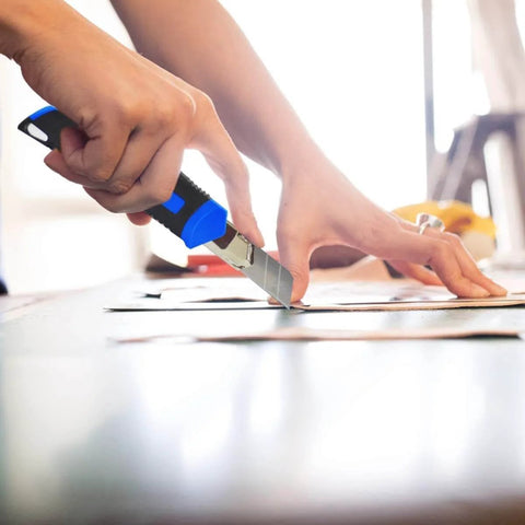 Person using a utility knife from 160-Piece Home Repair Tool Kit With Toolbox, Durable Chrome Steel Tools And TPR Grips, Blue Case.