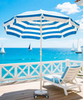 Striped beach umbrella with lounge chair on deck overlooking ocean and sailboats