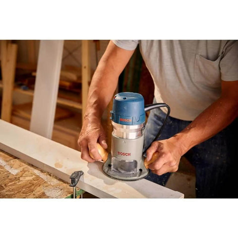 Person using Bosch 1617EVSPK Combo Router with plunge and fixed base, 2.25 HP motor, for woodworking on a table.