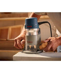 Person using 1617EVSPK Combo Router With Plunge And Fixed Base, 2.25 HP Motor, for precise woodworking