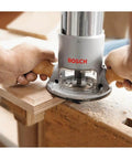Person using Bosch fixed-base router on wood, highlighting precise edge work with Fixed Base Router 2.25 HP 12 Amp Variable Speed 8000 to 25000 RPM.