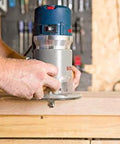 Person using Bosch 1617EVS fixed base router 2.25 HP 12 Amp variable speed 8000 to 25000 RPM for precise edge work and mortising on wood